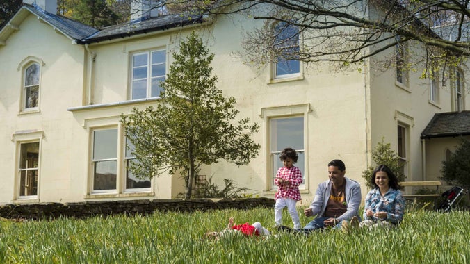 Two children and two adults sitting on the grass outside the house at Allan Bank and Grasmere